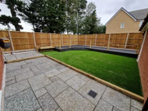 Grey Indian sandstone patio framed with sleepers in modern Ipswich garden renovation.