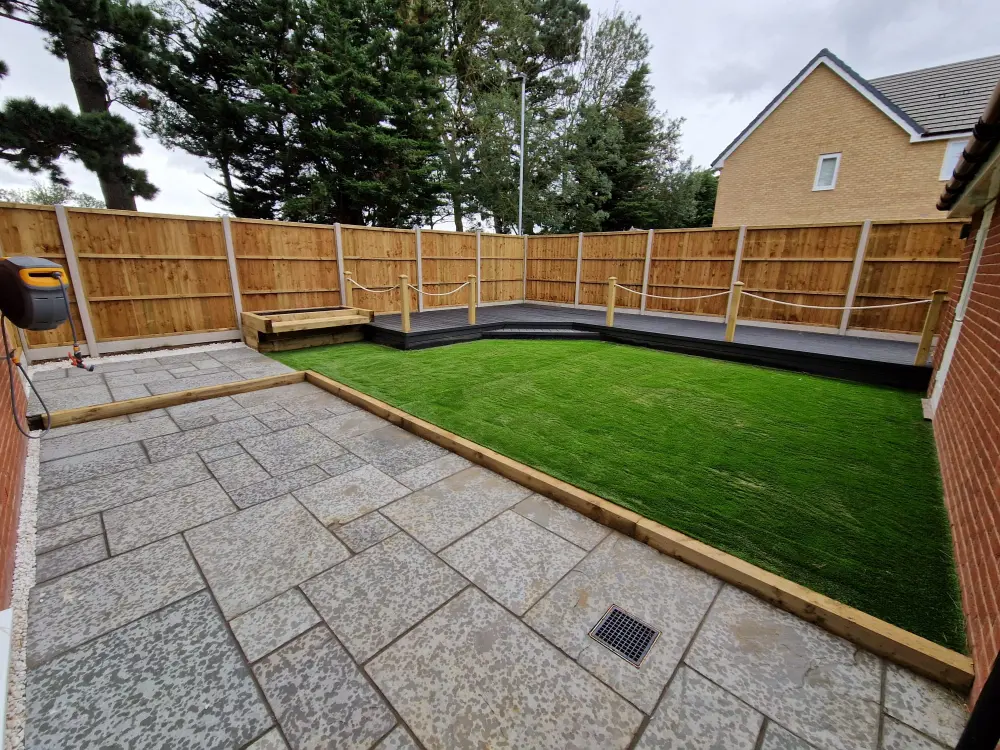 Grey Indian sandstone patio framed with sleepers in modern Ipswich garden renovation.