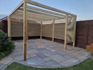 Custom timber pergola with slatted panels built over sandstone paving in Stowupland garden