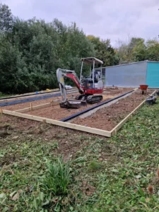 Timber shuttering and drainage channel layout during ground preparation for concrete pad in Stowmarket.